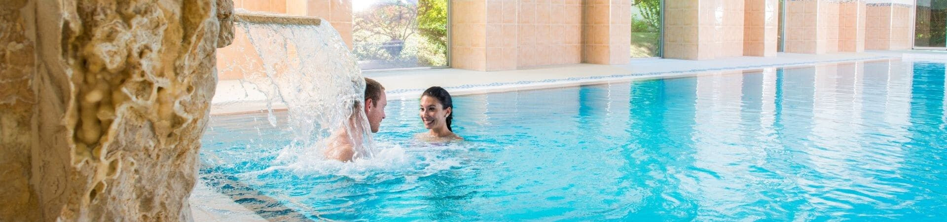 Coppia in piscina termale sotto una cascata - hotel di lusso