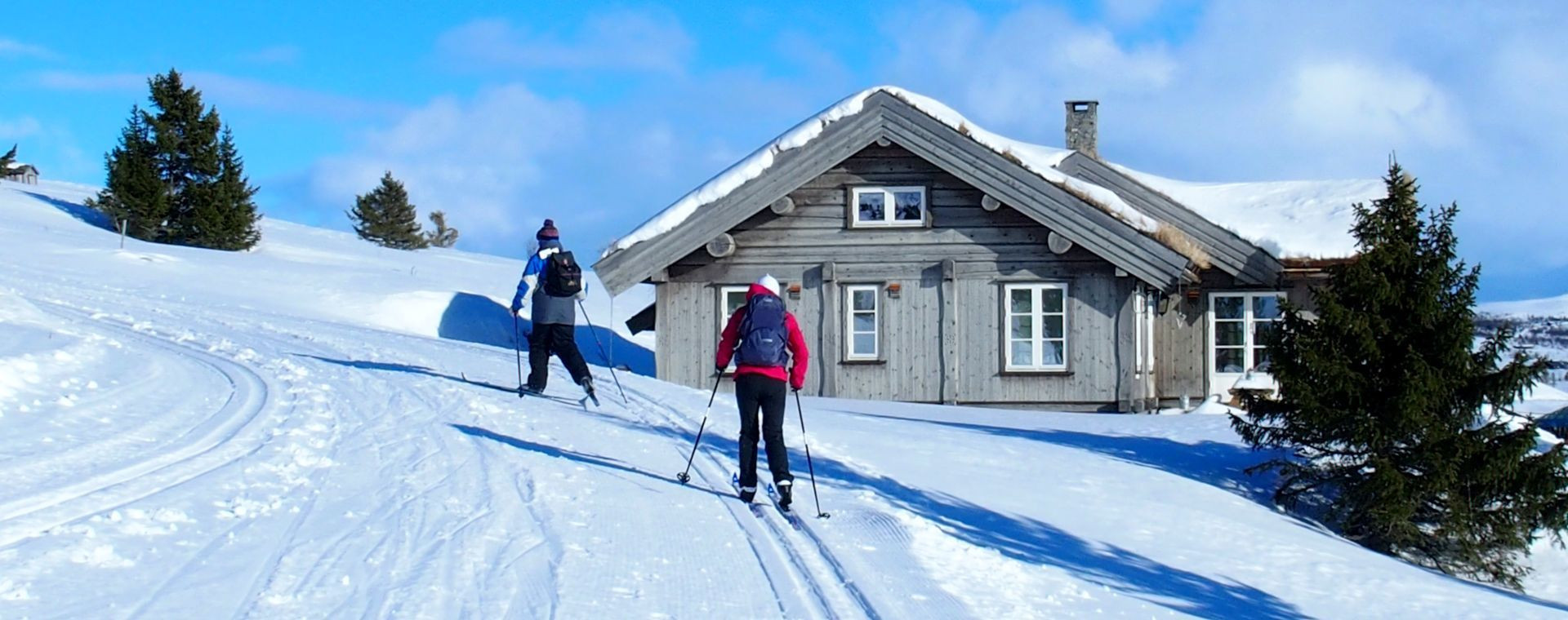 Sciatori di fondo vicino a uno chalet di legno - Scandinavia