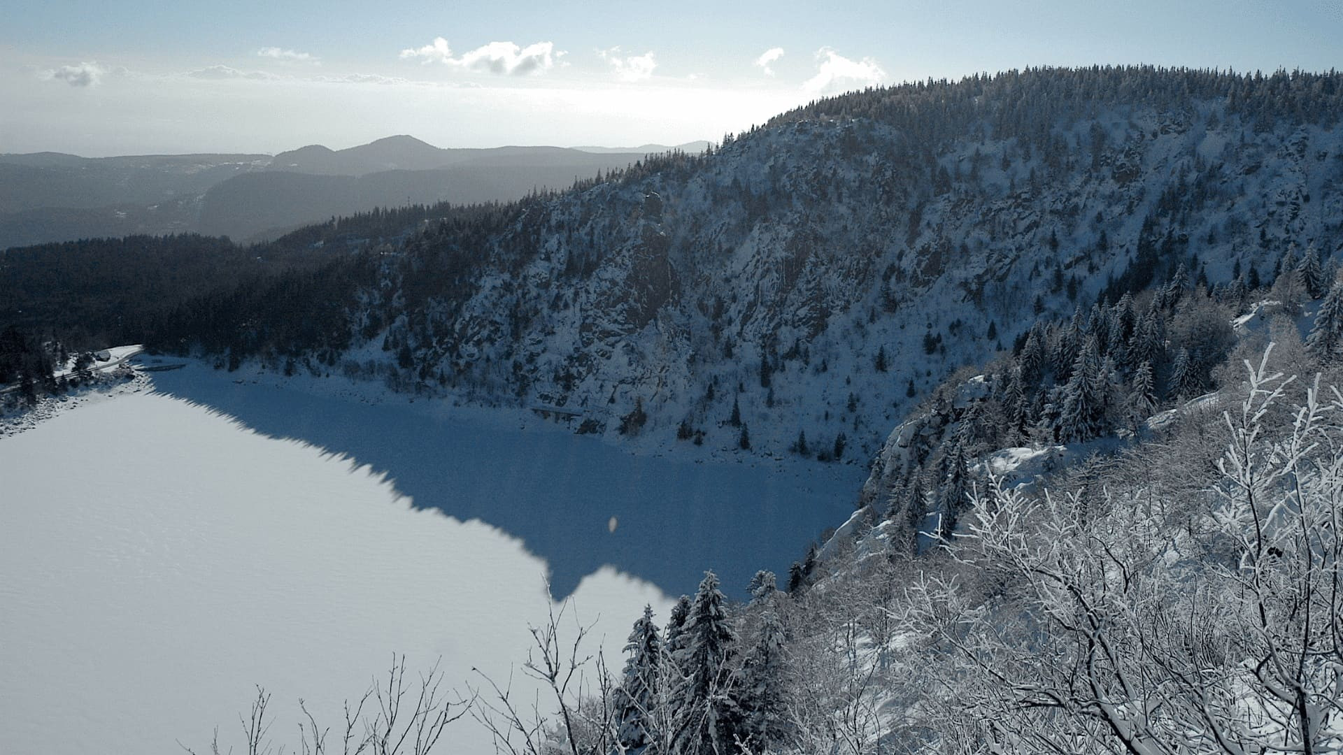 Lago ghiacciato in un circo boscoso innevato