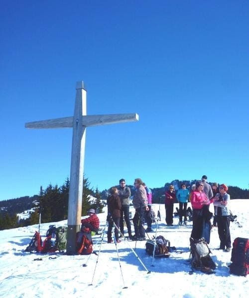 Gruppo presso la croce di una vetta innevata - Alpi