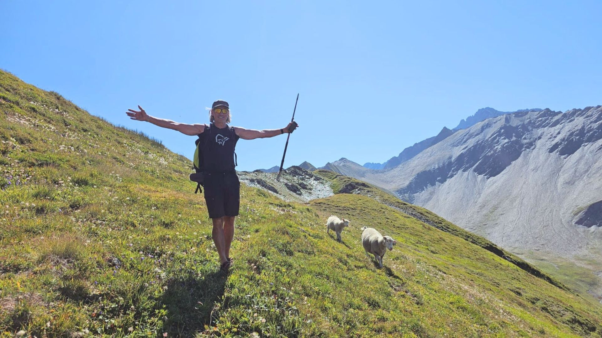Randonneuse bras ouverts suivie de moutons - Tour du Mont-Blanc - Alpes