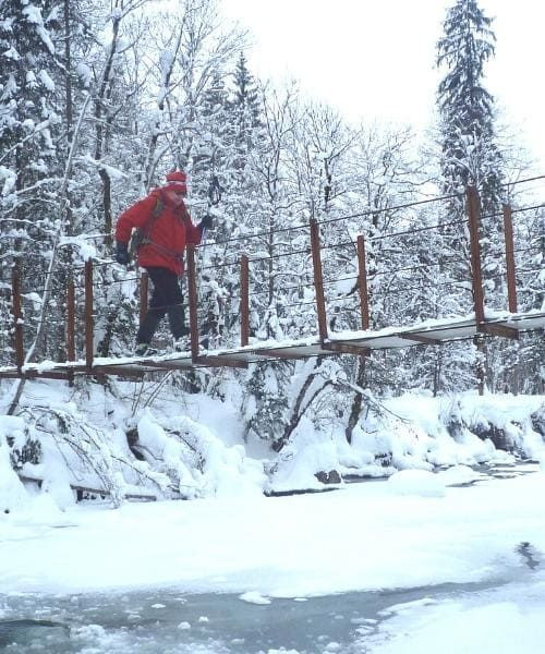 Escursionista attraversa un ponte innevato sul fiume Subersach - Vorarlberg - Austria