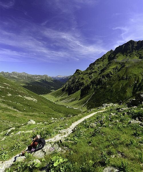 Randonneur au repos sur un col alpin verdoyant - Alpes