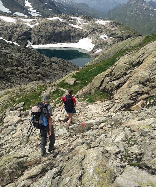 Randonneurs sur un sentier rocheux près d'un lac d'altitude - Alpes