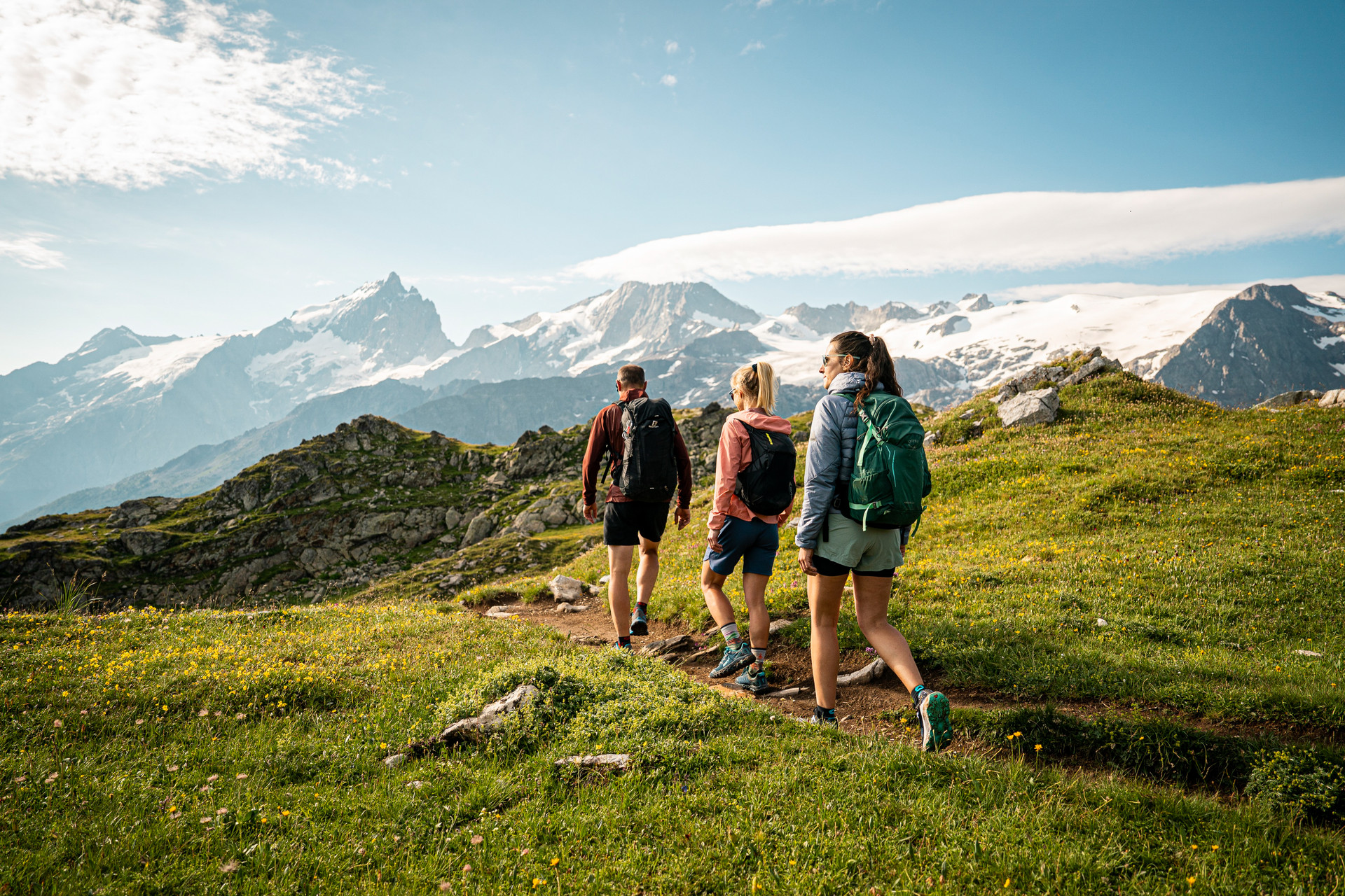 Tre escursionisti su un sentiero alpino di fronte ai ghiacciai degli Écrins