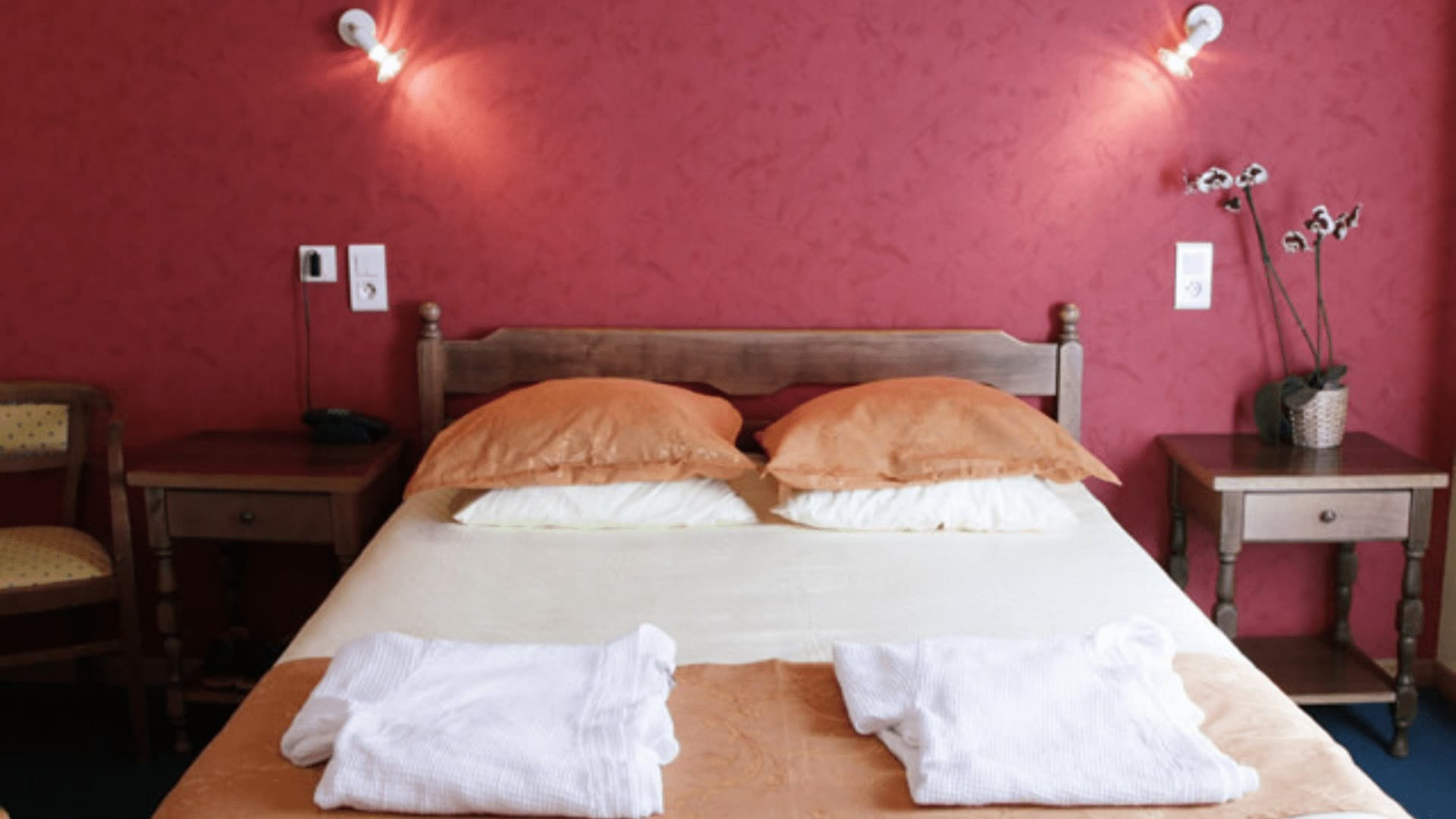 Camera d’hotel con pareti color lampone e cuscini arancioni - Francia