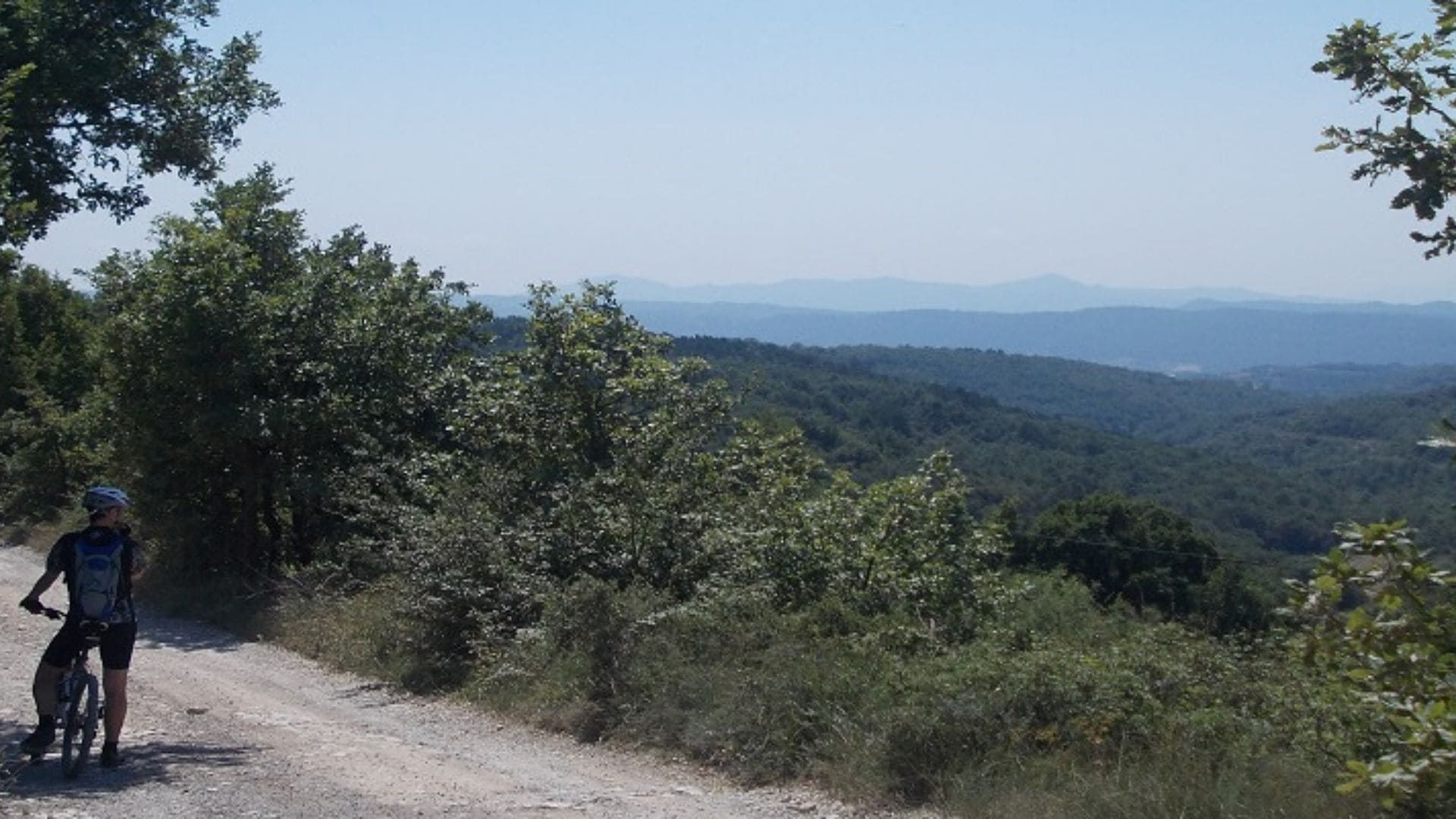 Ciclista su una pista davanti alle colline boscose - Catalogna - Spagna