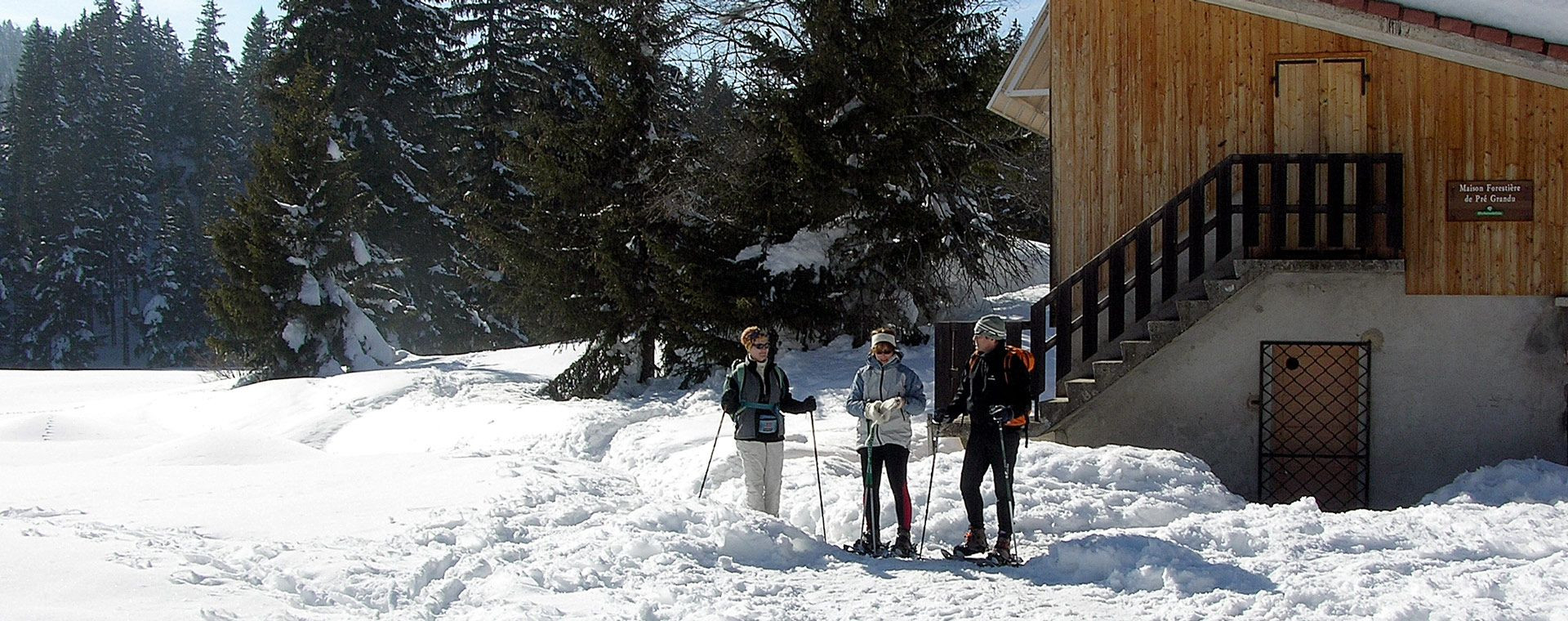 Escursionisti con le racchette da neve vicino a una casa forestale in inverno - Francia
