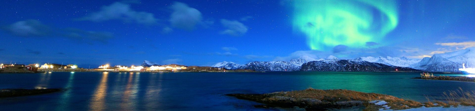 Aurora boreale sul villaggio costiero e sulle montagne innevate - Lofoten - Norvegia