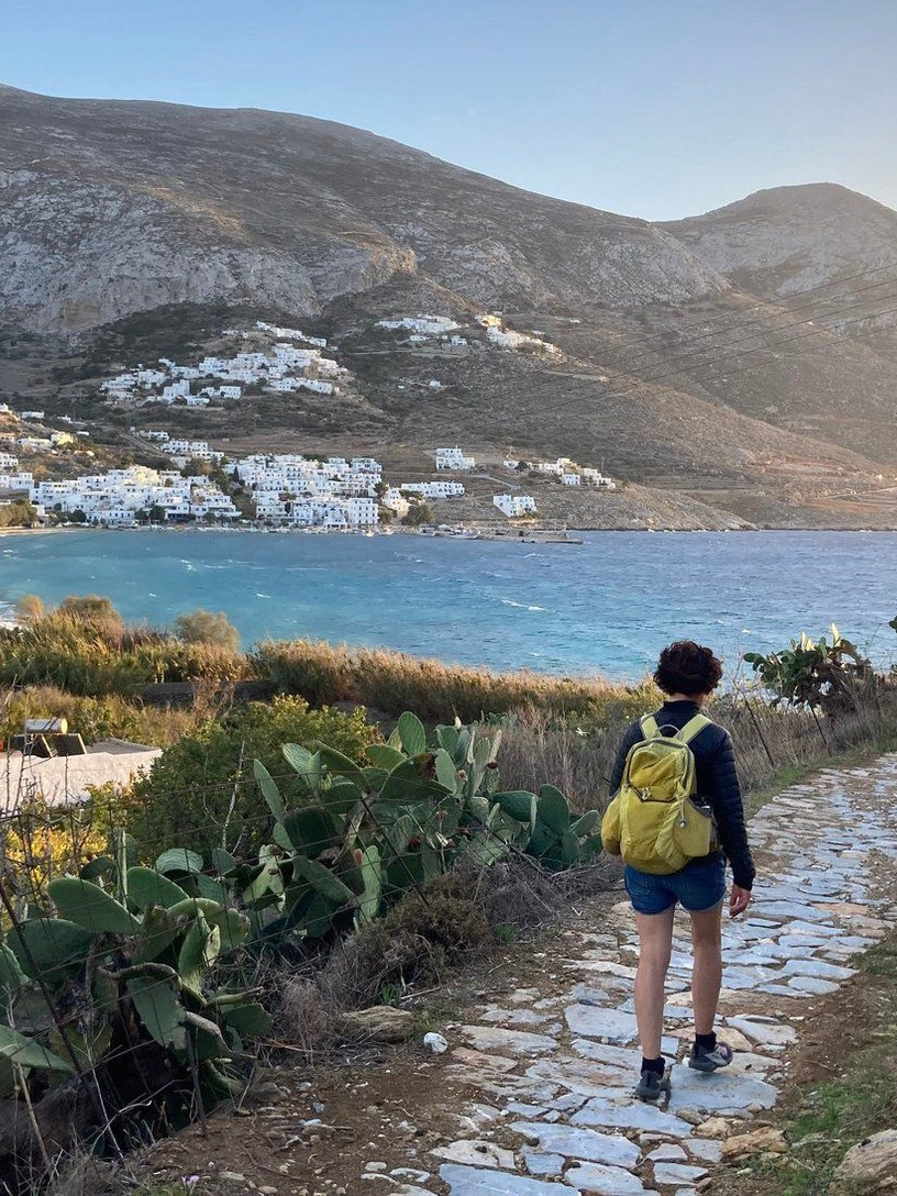 Escursionista su un sentiero lastricato sopra la baia di Amorgos, nelle Cicladi