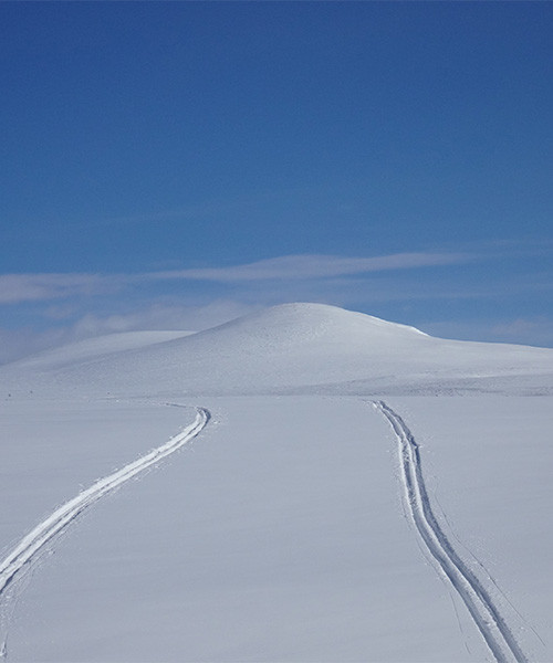 Tracce di sci su un altopiano innevato verso una cupola bianca