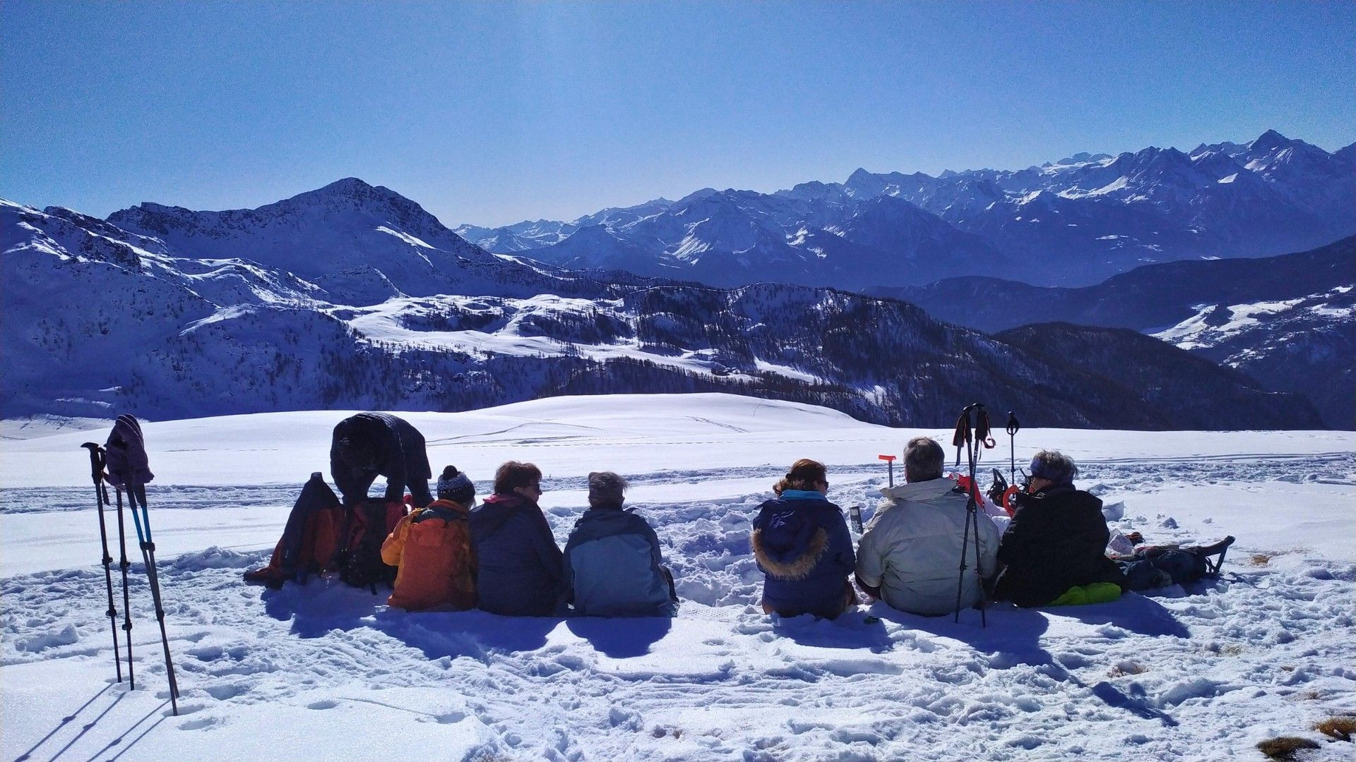 Pause d'un groupe en raquettes face aux sommets enneigés - Alpes italiennes - Italie