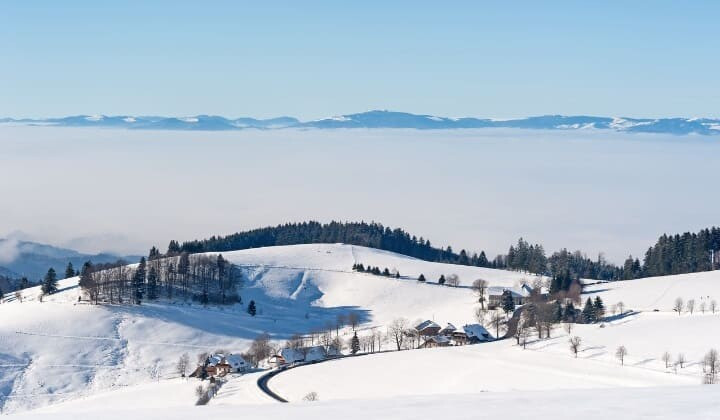 Colline innevate sopra un mare di nuvole