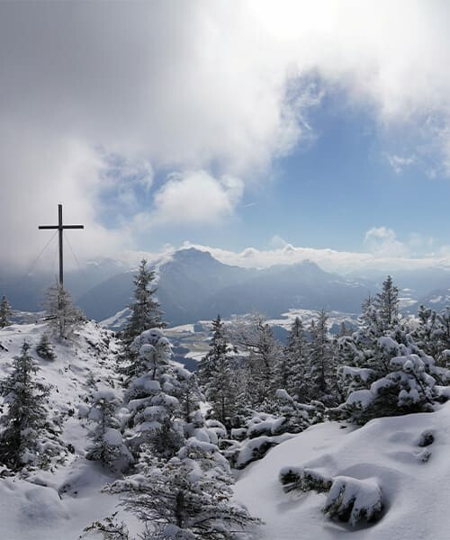 Croce di vetta e montagne innevate in inverno - Alpi