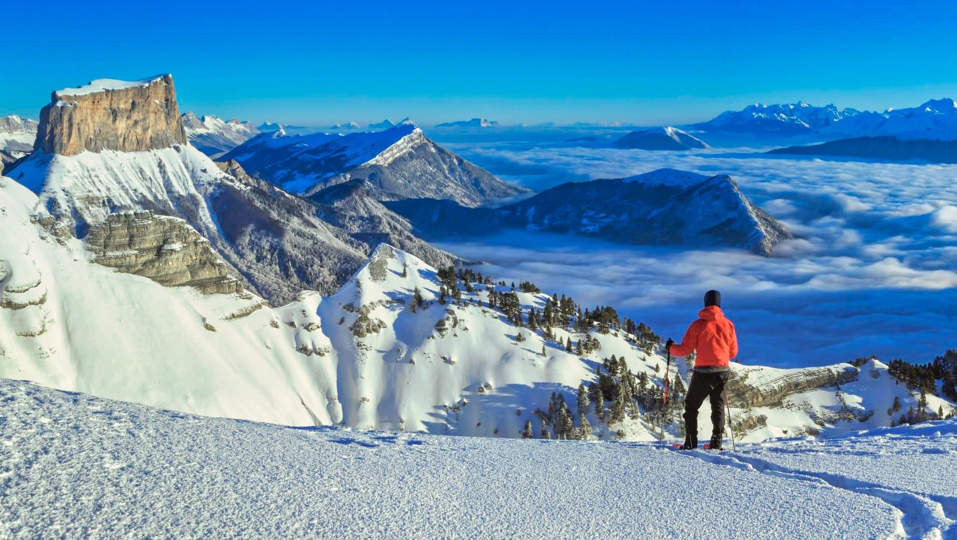 Escursionista con le racchette da neve di fronte al Mont Aiguille e al mare di nuvole - Vercors - Francia